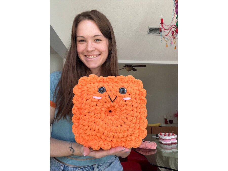 Woman holding a giant knitted cheez-it cracker